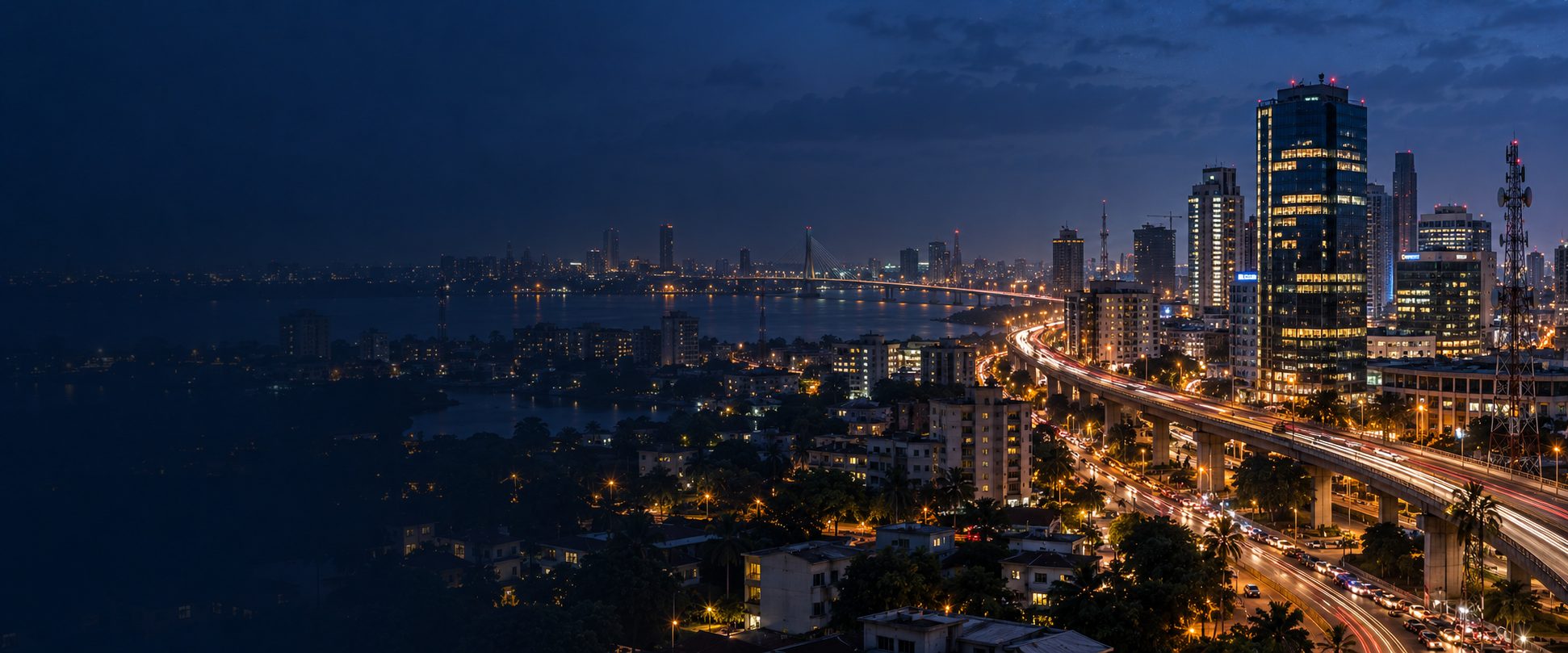 A coastal city skyline lit up at dusk, with a bridge and elevated highway leading into the business district.